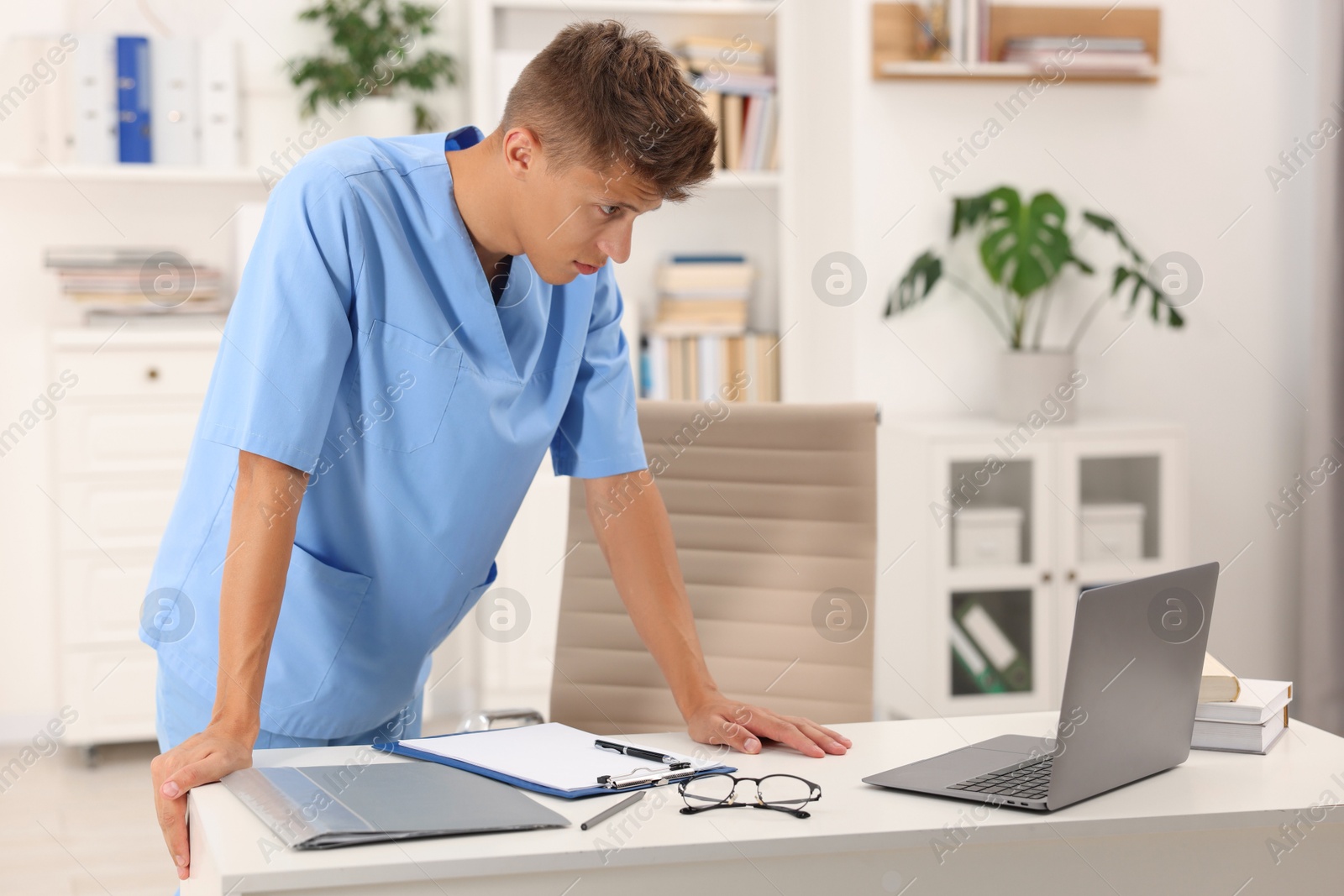 Photo of Medical student in uniform studying at table indoors