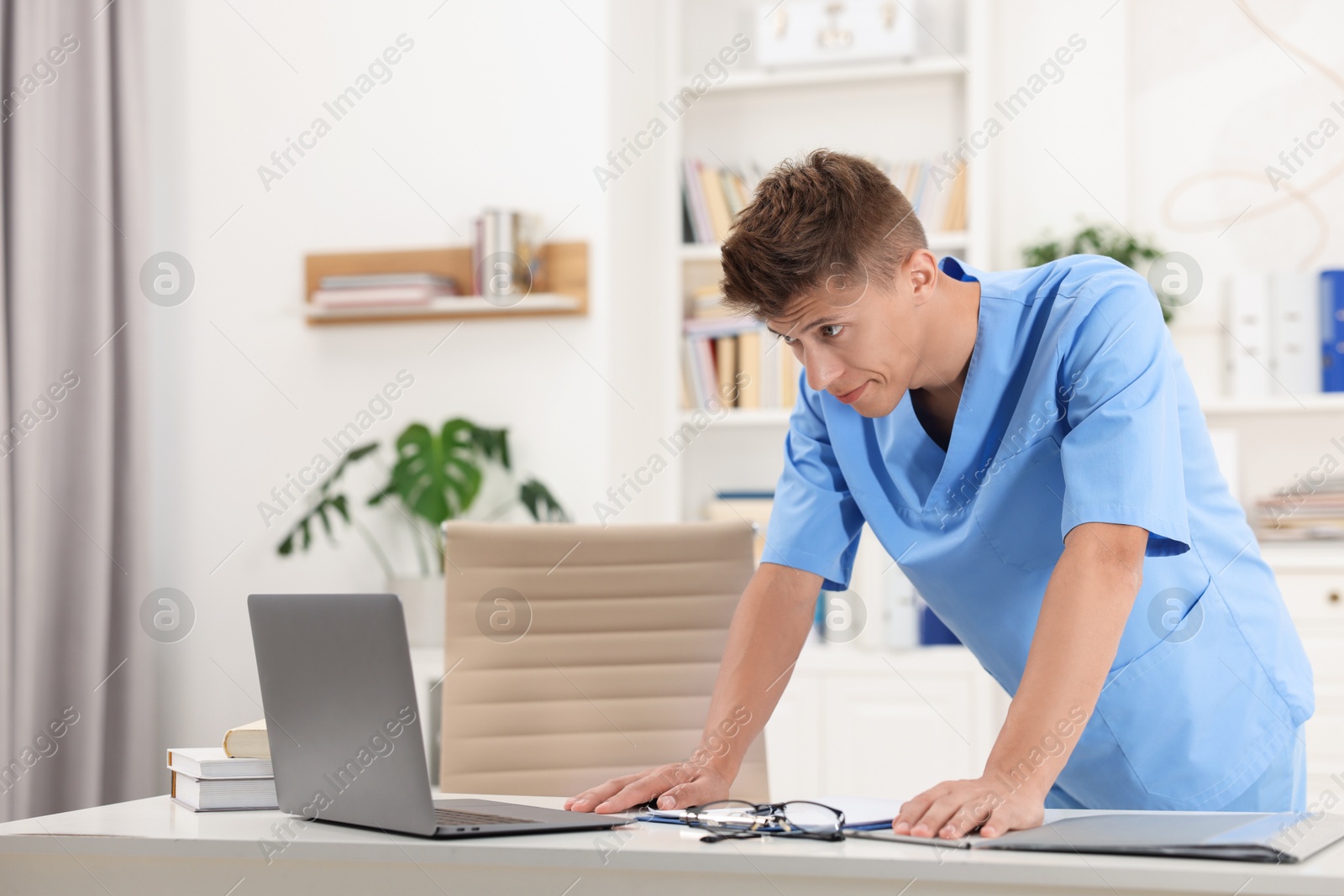 Photo of Medical student in uniform studying at table indoors