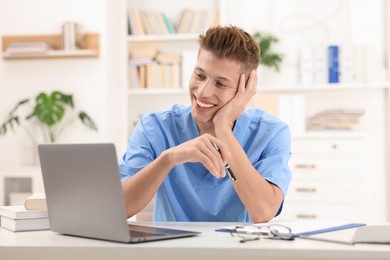 Photo of Medical student in uniform studying at table indoors