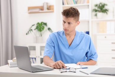 Photo of Medical student in uniform studying at table indoors