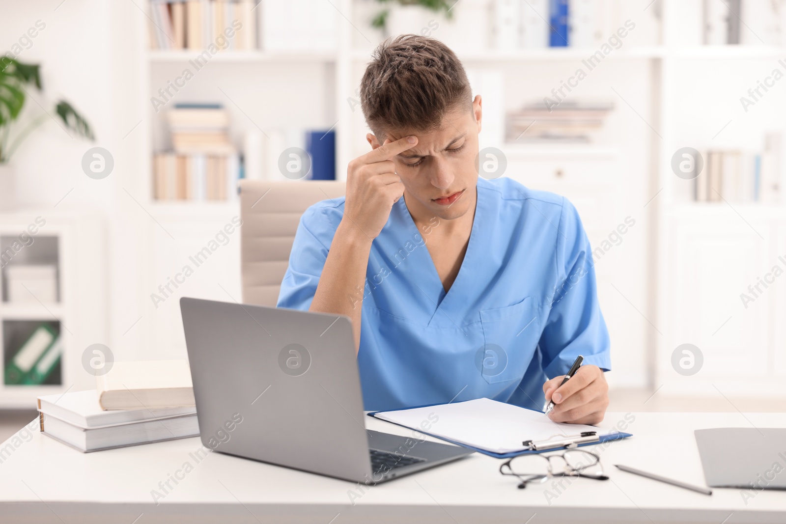 Photo of Medical student in uniform studying at table indoors