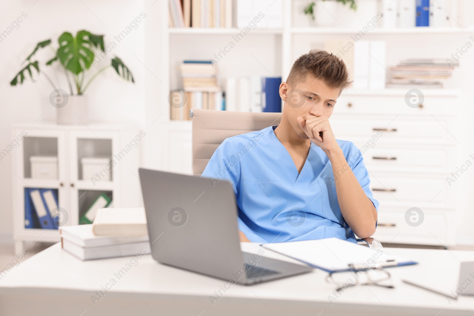 Photo of Medical student in uniform studying at table indoors