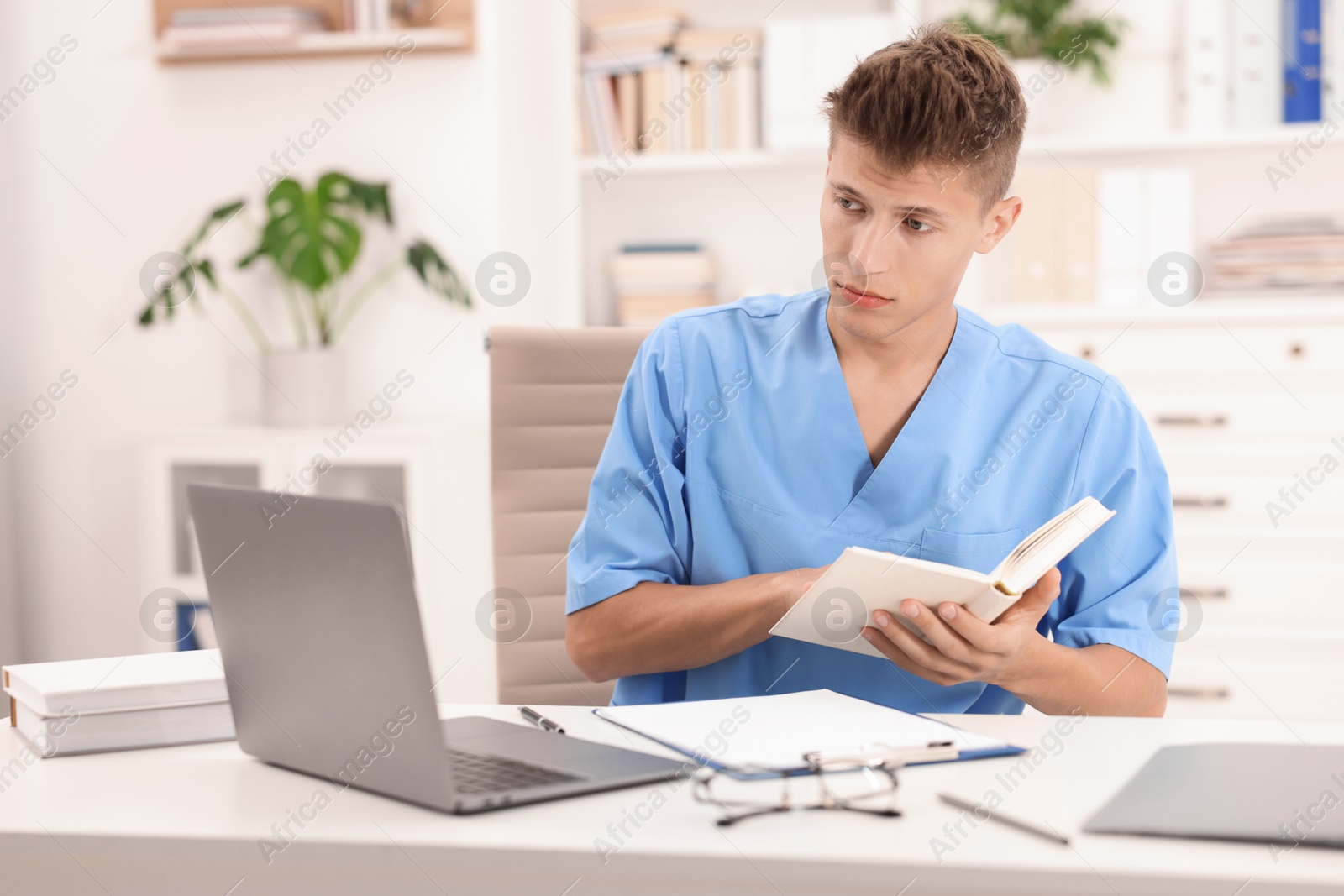 Photo of Medical student with book studying at table indoors