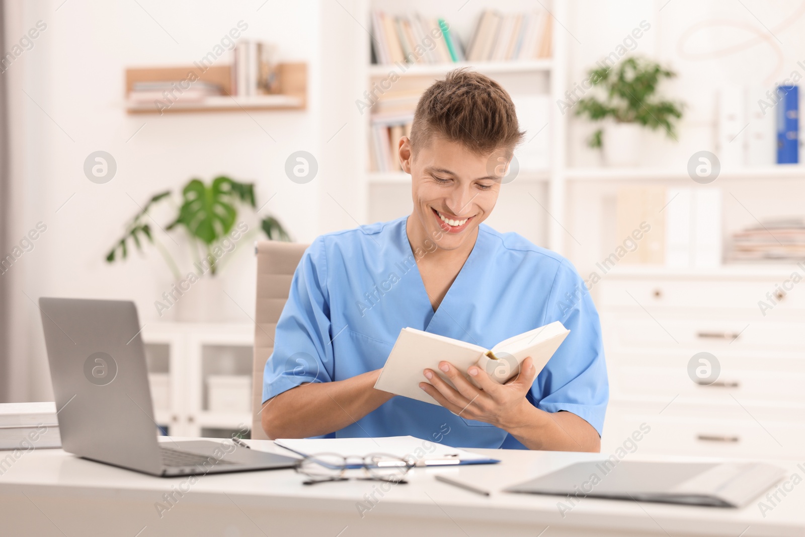 Photo of Medical student with book studying at table indoors