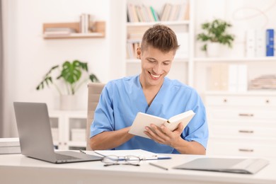 Photo of Medical student with book studying at table indoors