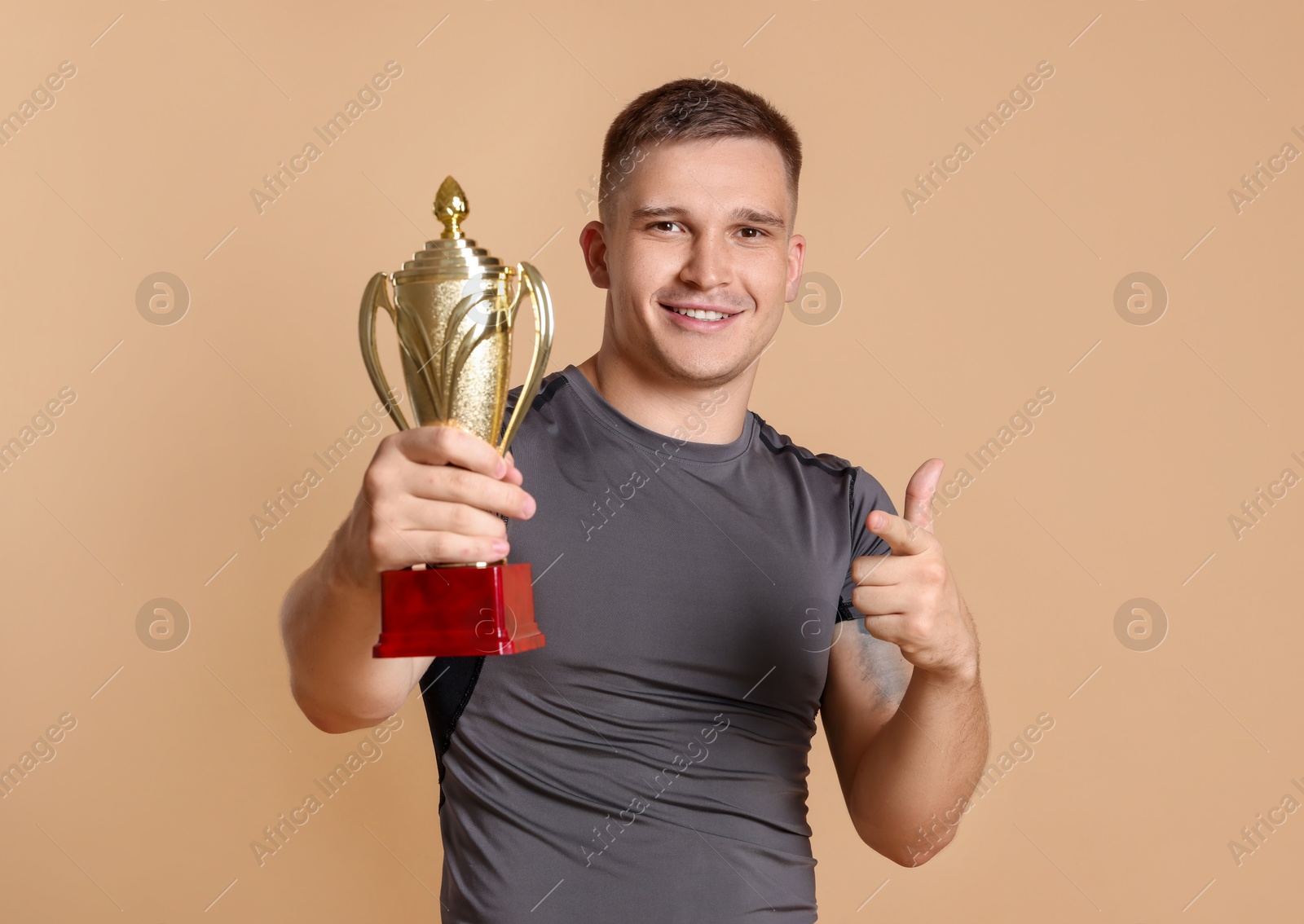 Photo of Happy winner with golden trophy cup on beige background