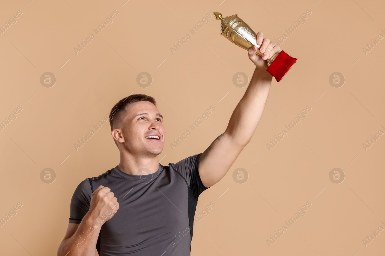 Photo of Happy winner with golden trophy cup on beige background