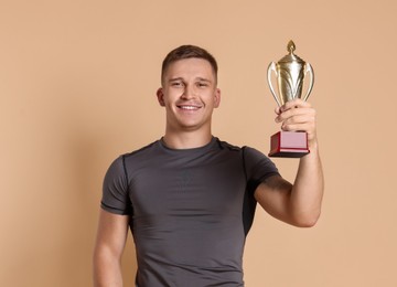 Photo of Happy winner with golden trophy cup on beige background