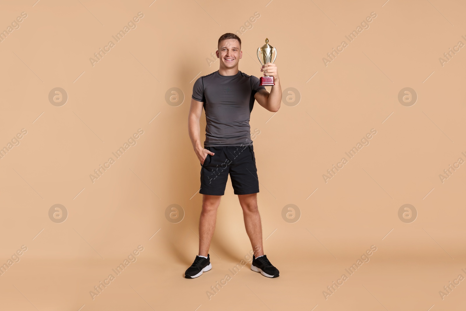 Photo of Happy winner with golden trophy cup on beige background