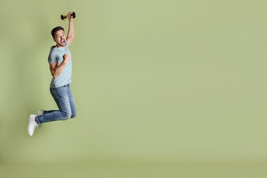 Photo of Happy winner with golden trophy cup jumping on pale olive background