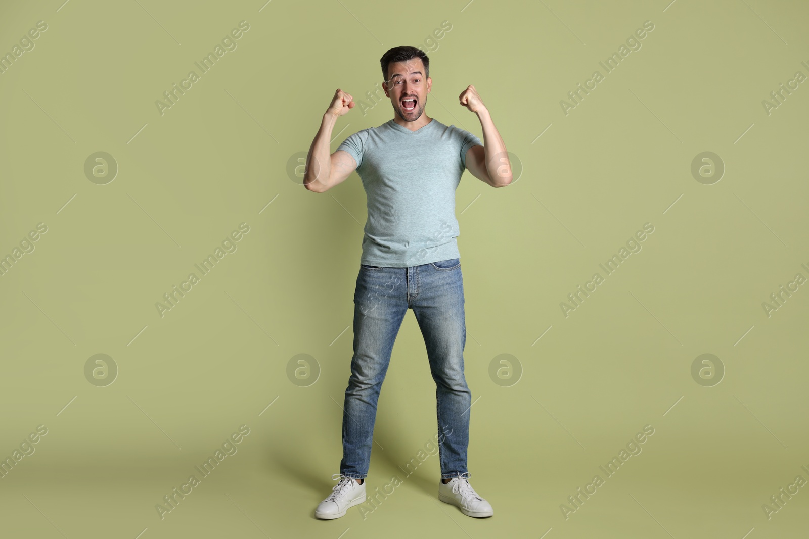 Photo of Portrait of happy winner on pale olive background