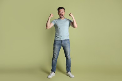 Portrait of happy winner on pale olive background