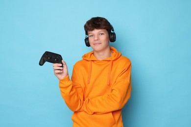 Teenage boy with controller on light blue background