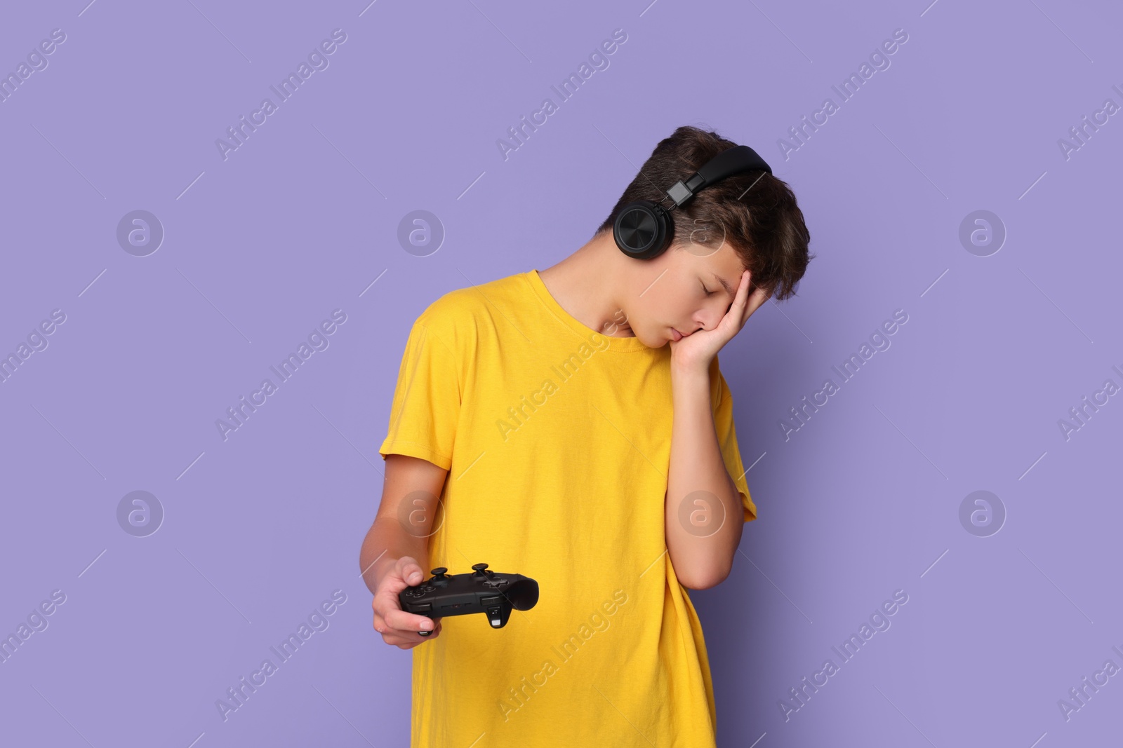 Photo of Teenage boy in headphones with controller on violet background