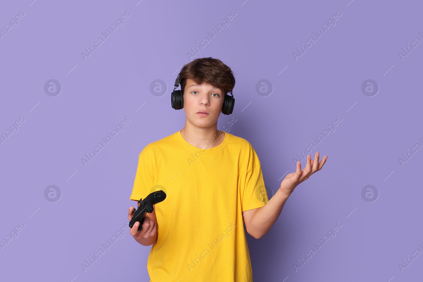 Photo of Teenage boy in headphones with controller on violet background