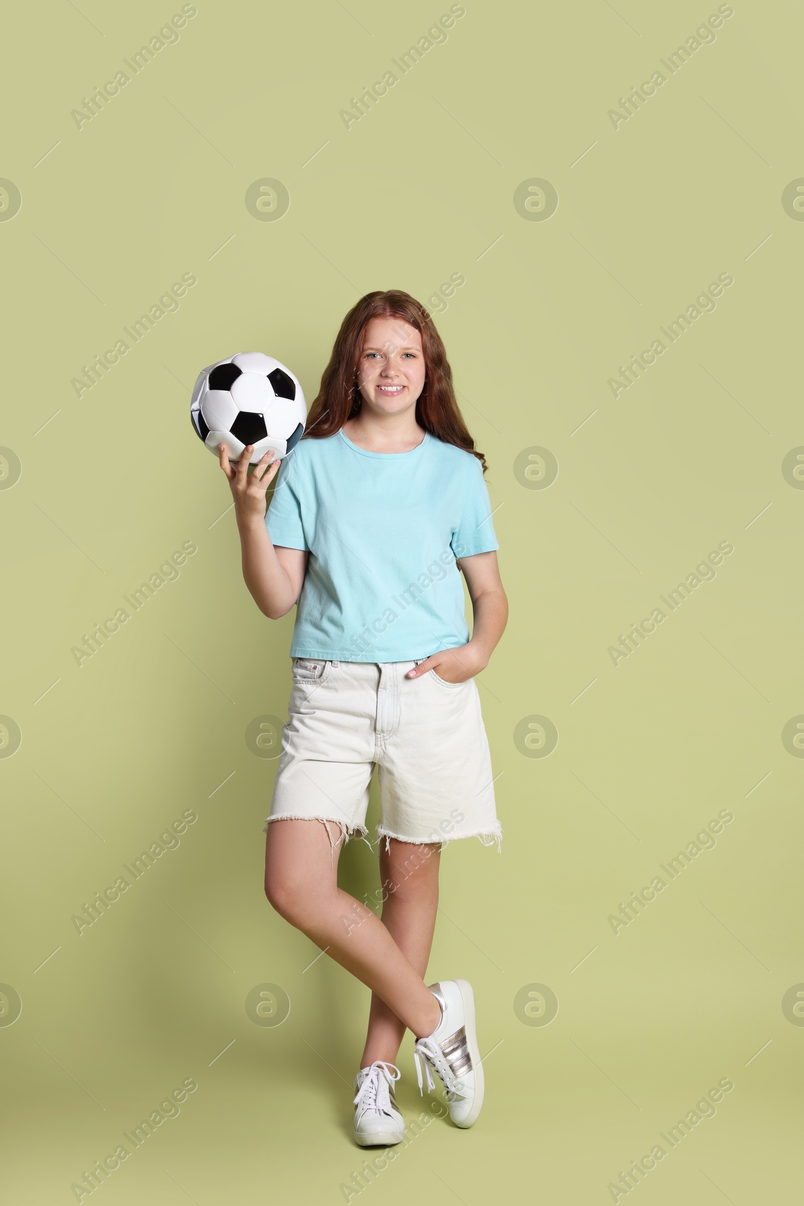 Photo of Smiling teenage girl with soccer ball on green background