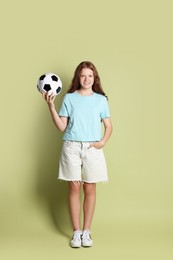 Smiling teenage girl with soccer ball on green background