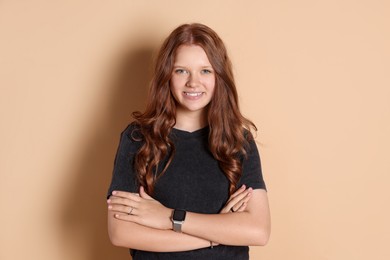 Photo of Smiling teenage girl with crossed arms on beige background