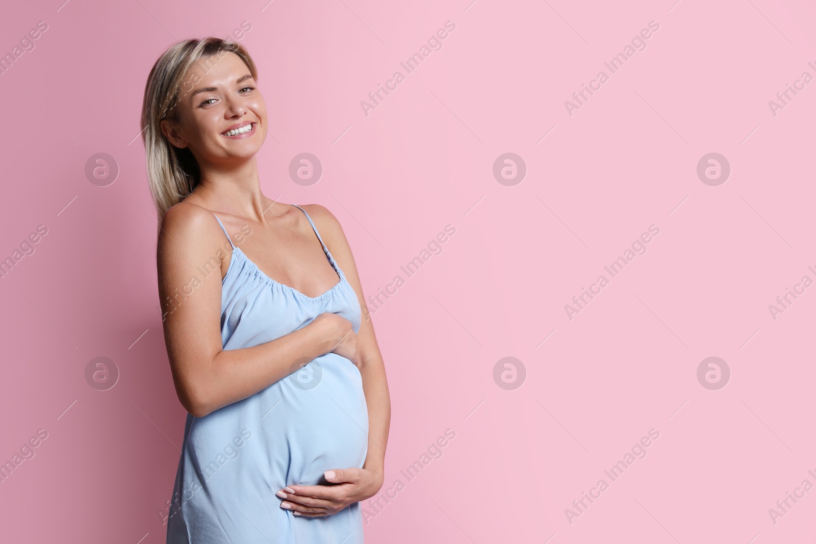 Photo of Portrait of beautiful pregnant woman on pink background, space for text