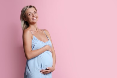 Portrait of beautiful pregnant woman on pink background, space for text