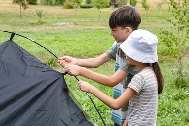 Photo of Girl and her brother setting up camping tent outdoors