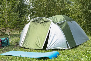 Tent and other camping equipment on green grass outdoors