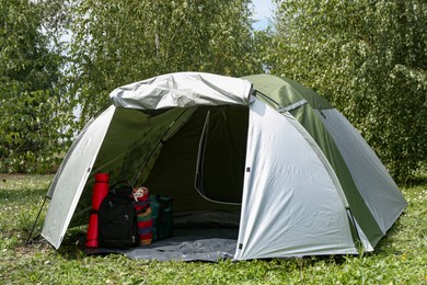 Tent and other camping equipment on green grass outdoors