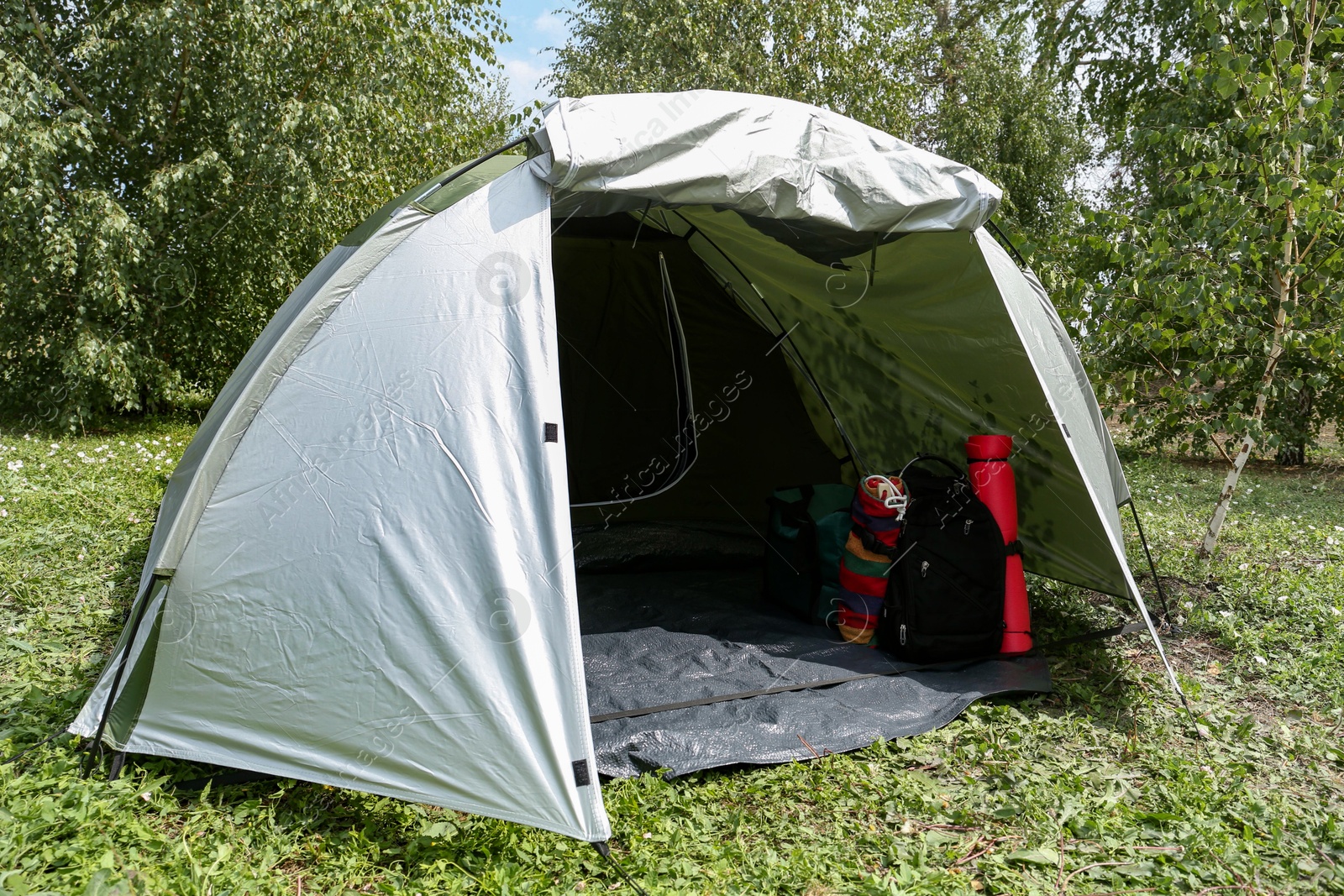 Photo of Tent and other camping equipment on green grass outdoors