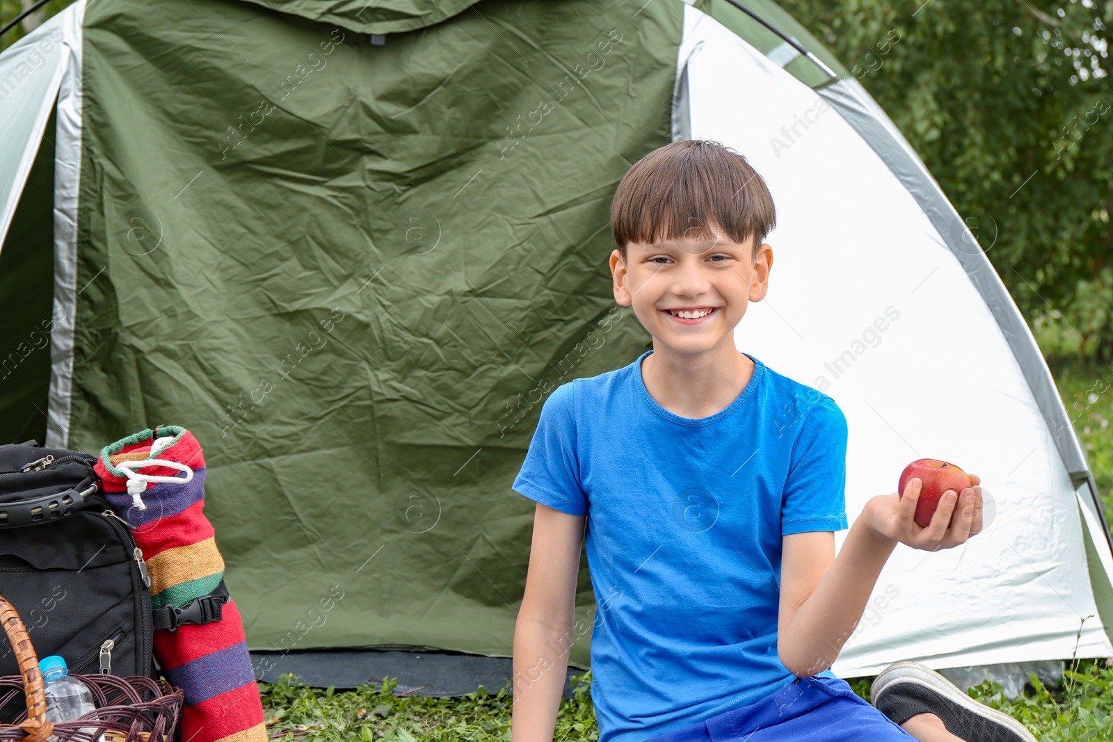 Photo of Boy with apple near camping tent outdoors