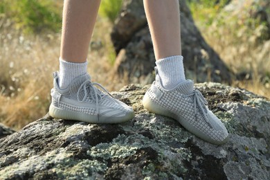 Photo of Little girl walking on stones outdoors, closeup