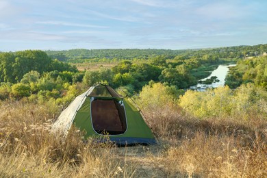 One camping tent among plants outdoors on sunny day. Space for text