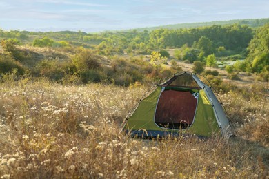 Photo of One camping tent among plants outdoors. Space for text