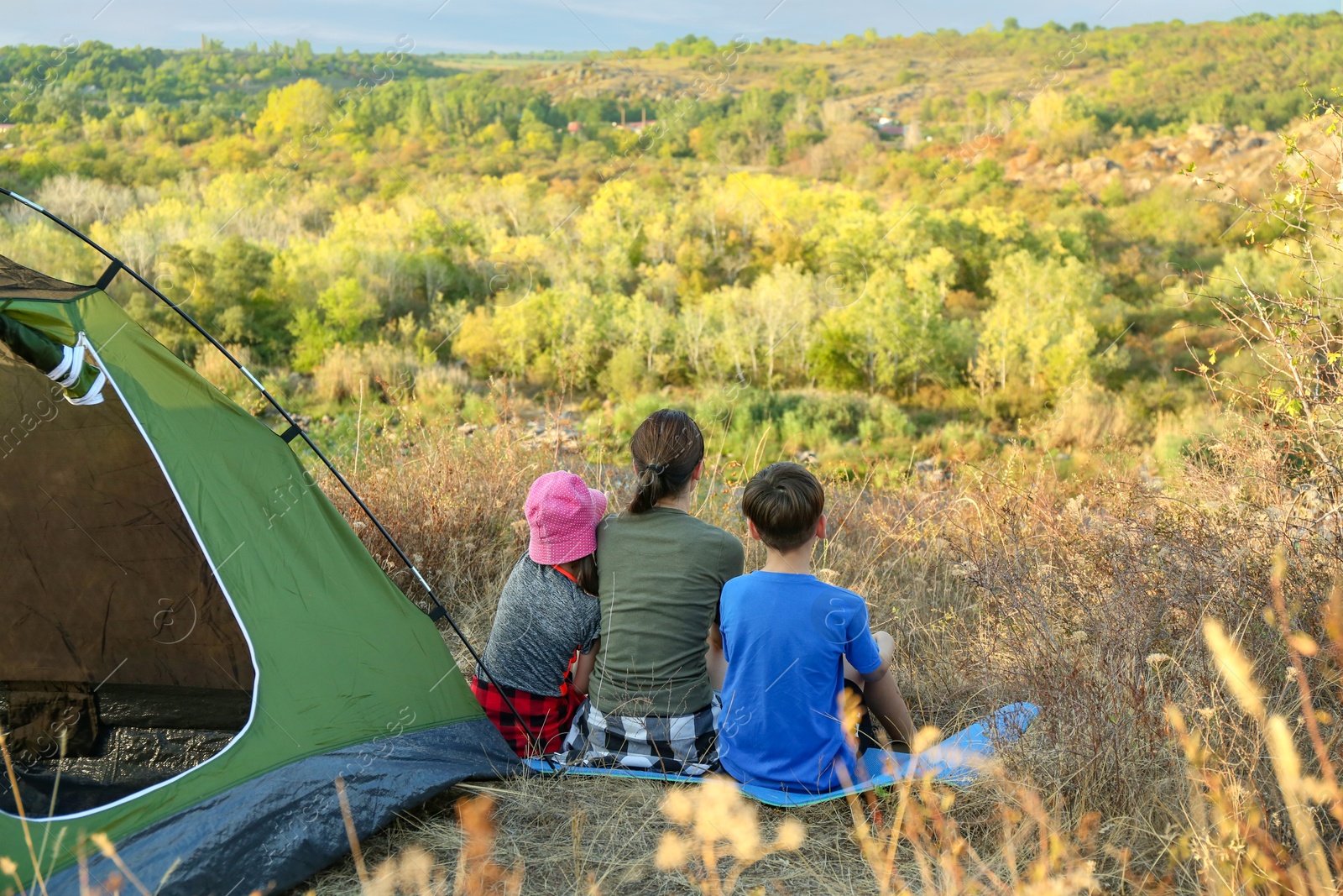 Photo of Family enjoying picturesque view near camping tent, back view