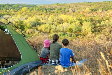 Family enjoying picturesque view near camping tent, back view