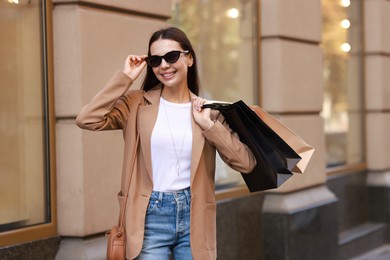 Photo of Happy woman with many shopping bags outdoors