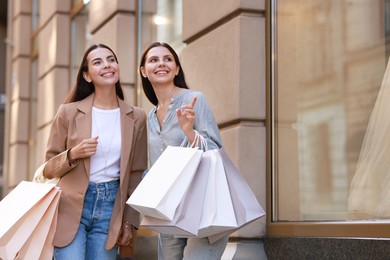 Photo of Happy women with colorful shopping bags outdoors