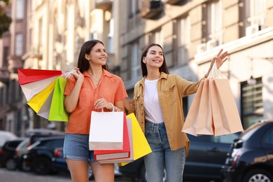 Photo of Happy women with colorful shopping bags outdoors