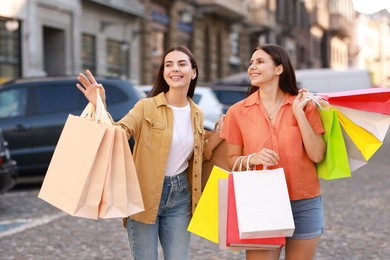 Photo of Happy women with colorful shopping bags outdoors