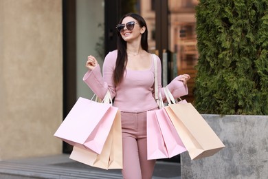 Photo of Happy woman with colorful shopping bags outdoors