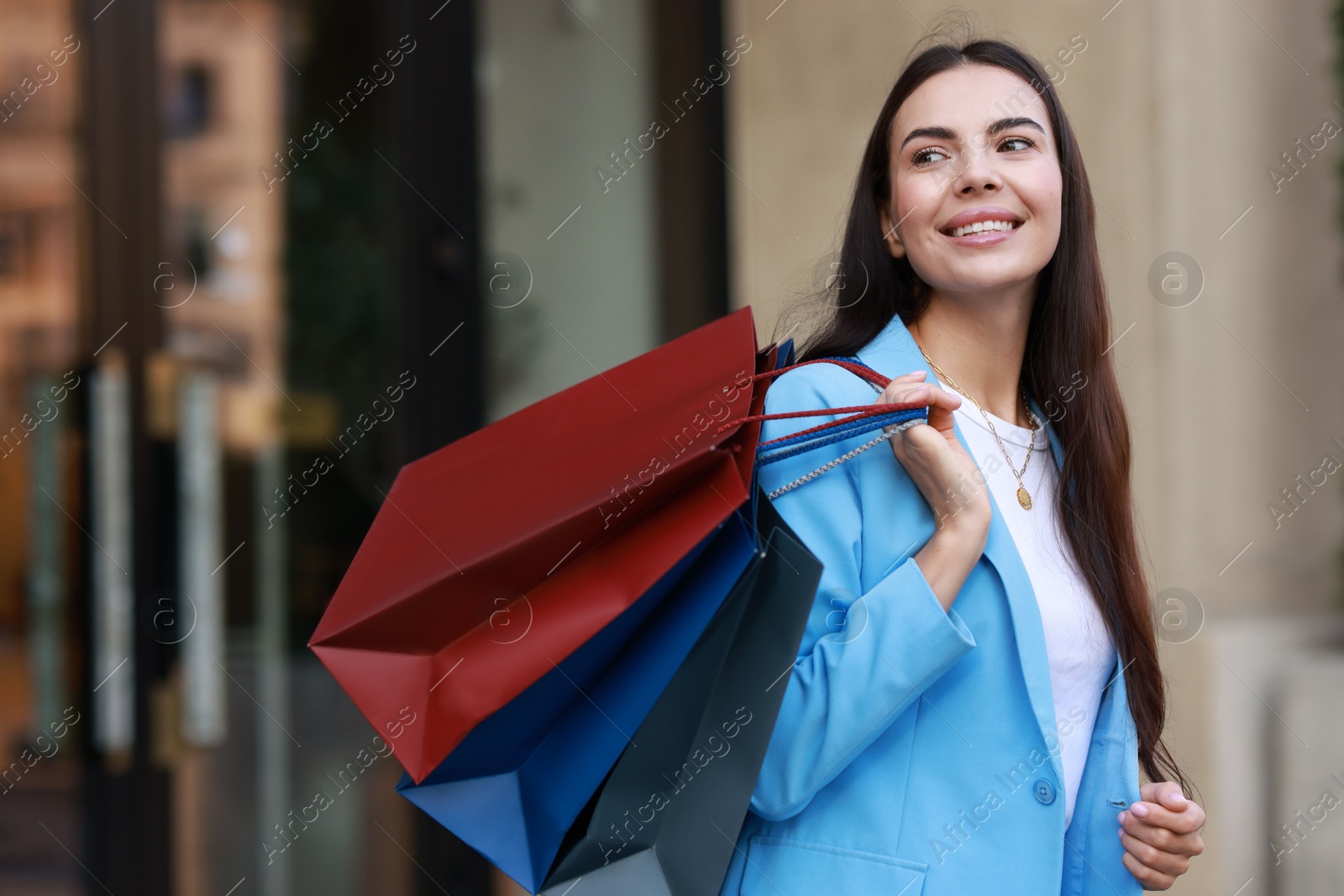 Photo of Happy woman with colorful shopping bags outdoors