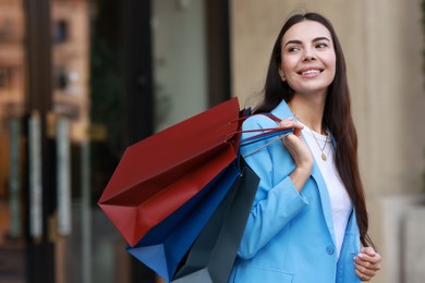 Photo of Happy woman with colorful shopping bags outdoors