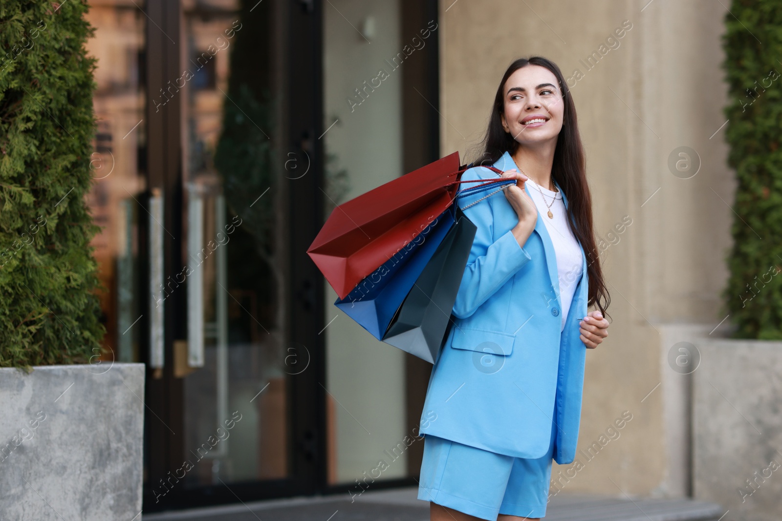 Photo of Happy woman with colorful shopping bags outdoors