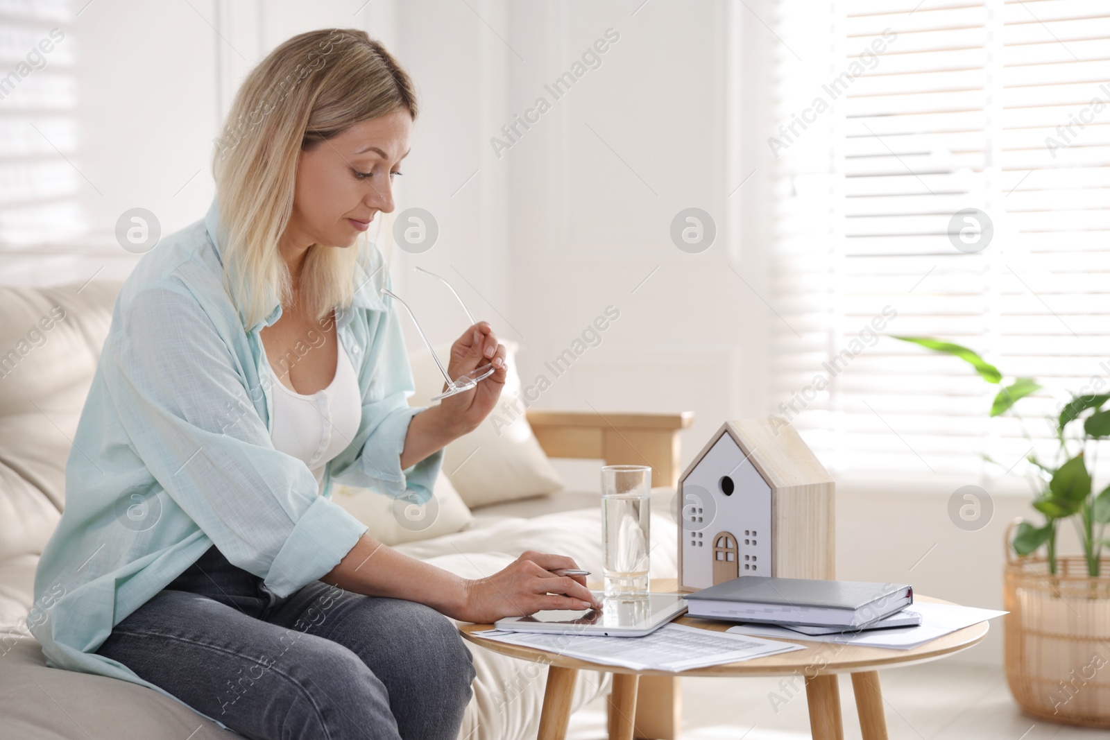 Photo of Budget planning. Woman using tablet at table indoors