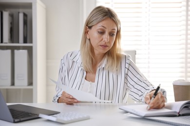 Budget planning. Woman with document taking notes at table indoors