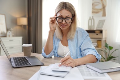 Budget planning. Woman using calculator at table indoors