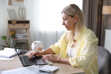 Photo of Budget planning. Woman using laptop at table indoors