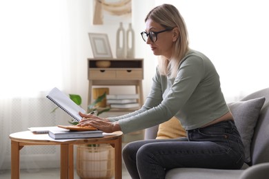 Photo of Budget planning. Woman using calculator while working with accounting document at table indoors