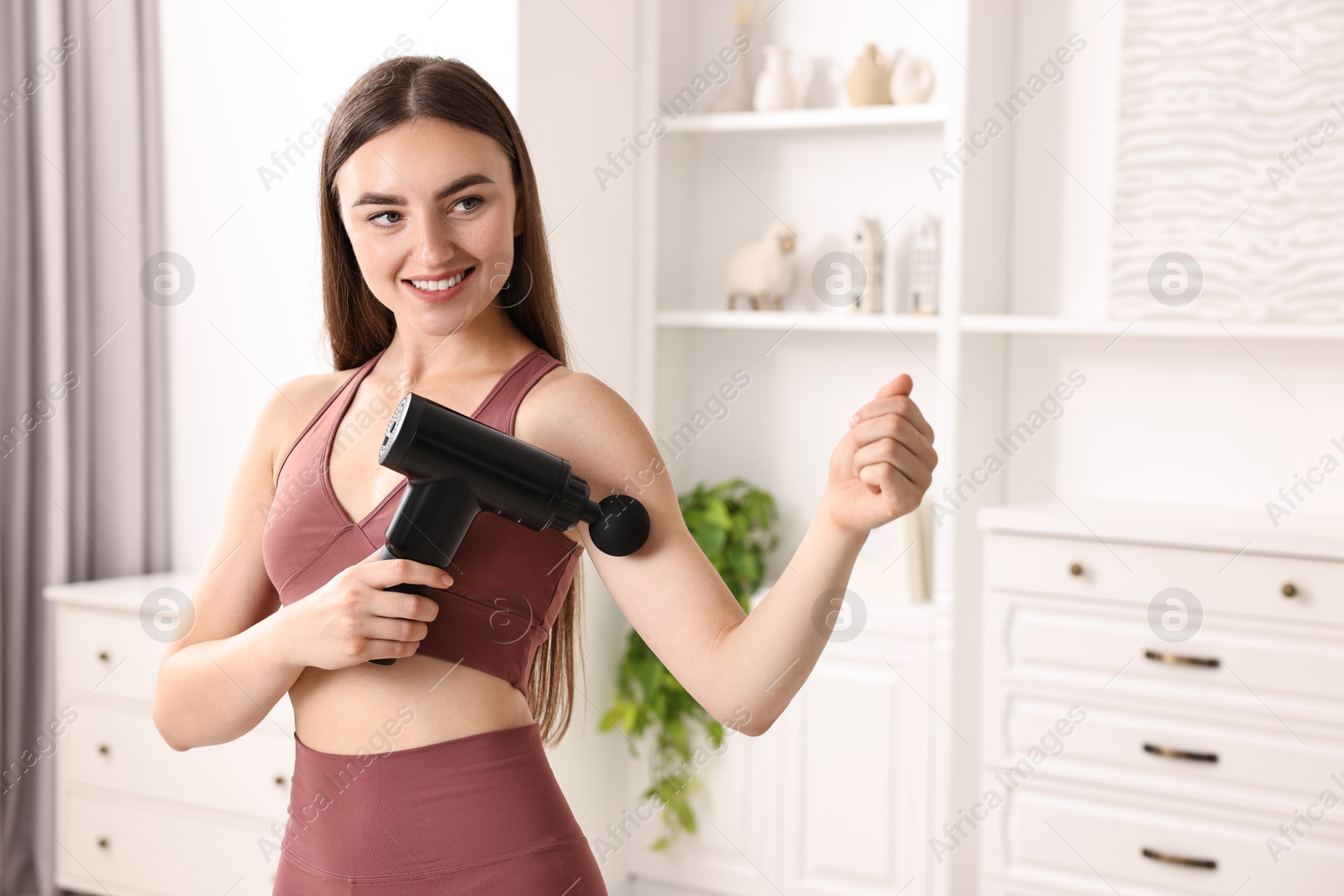 Photo of Woman using percussive massager to relieve bicep at home. Space for text