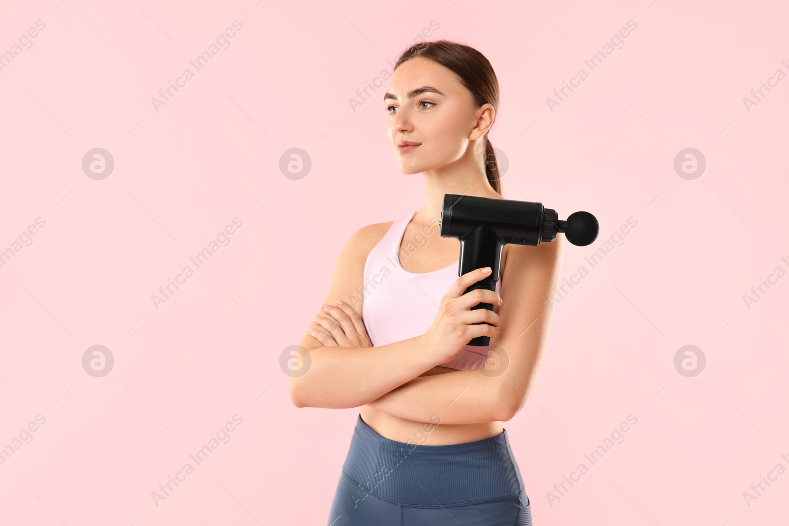 Photo of Young woman with percussive massager on pink background. Space for text