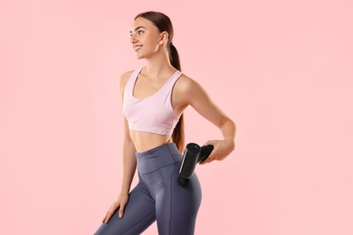 Woman using percussive massager to relax hip muscles on pink background